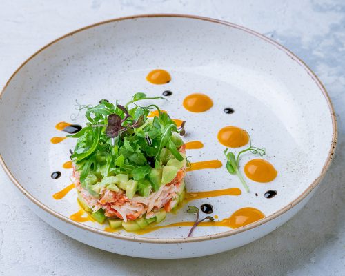 crab tartare with avocado and aragula on plate