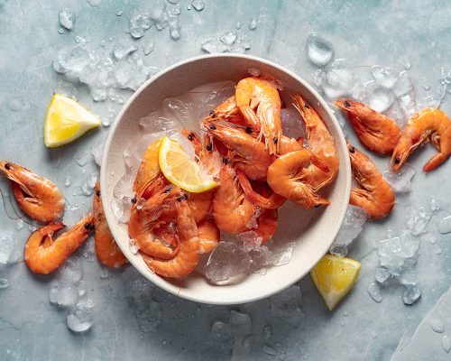 Healthy food. Fresh shrimps with ice on plate on light background top view